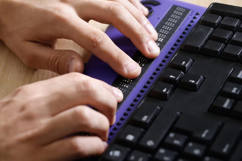 Eine blinde Person nutzt einen Computer mit einer Braillezeile. 7 Tipps für barrierefreie Websites.